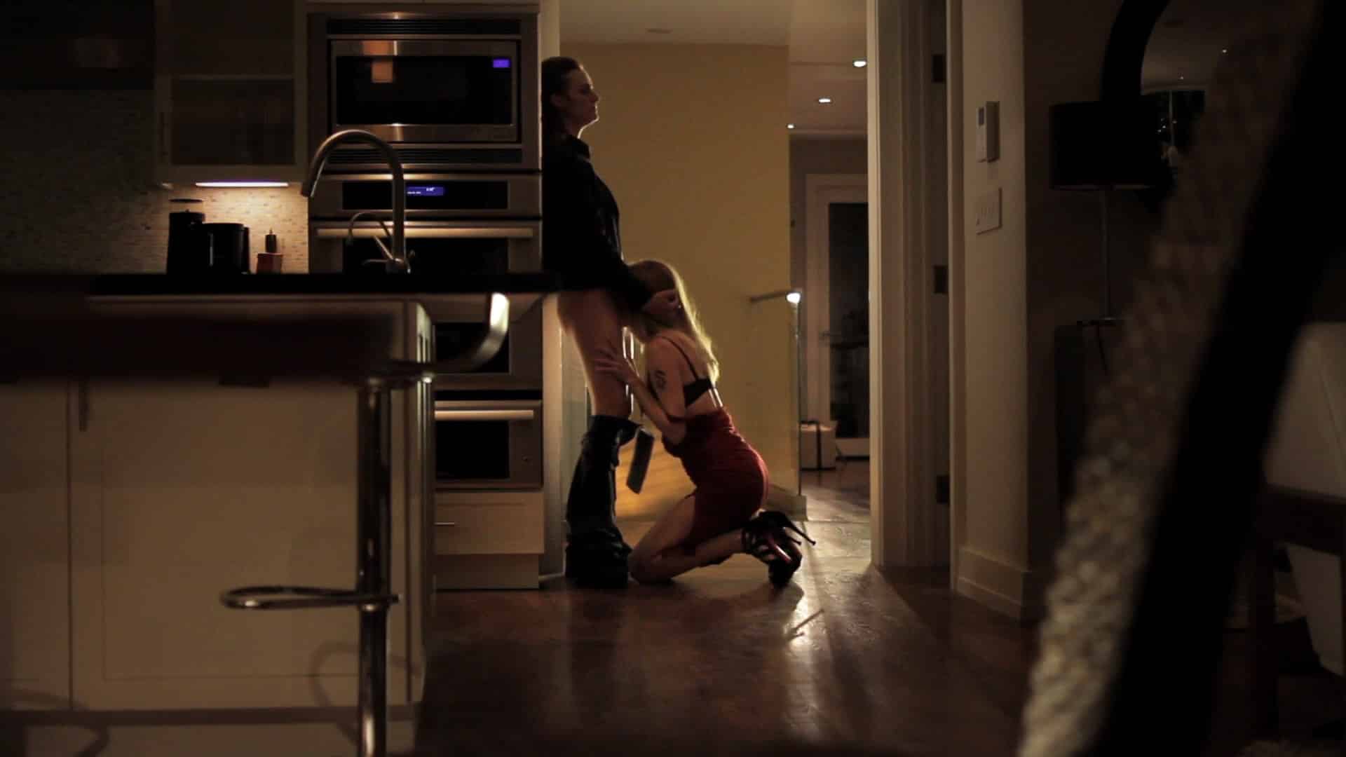 Heather kneels in front of Diane Farr, giving her oral sex