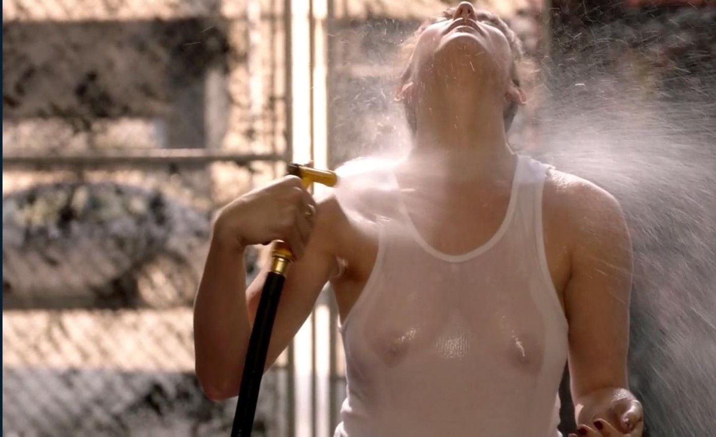 Isidora Goreshter in a white tank top sprays her shirt to make it wet and see-through, grabbing her breasts